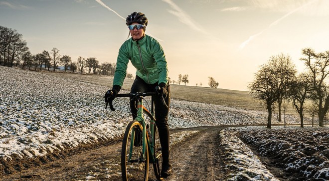 Frau mit Primaloftjacke und Gravelbike