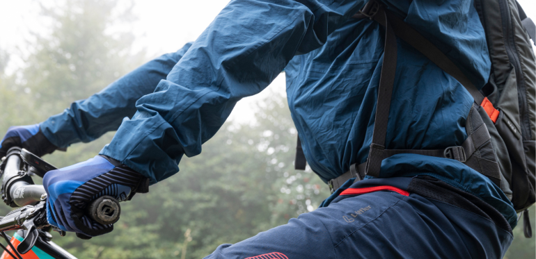 Mountainbiker sitting on his bike with dark blue rain jacket