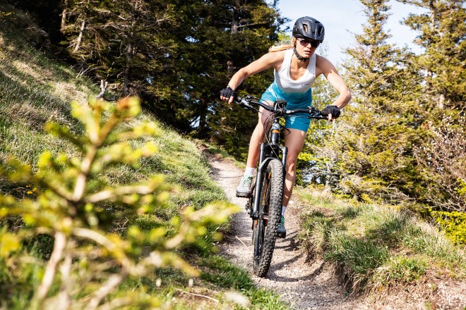 Woman riding a mountain bike down a trail.
