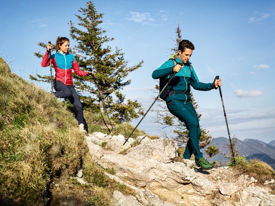Woman and man going down a trail with walking sticks.