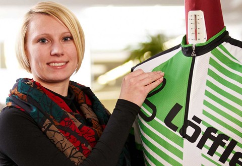 Woman presenting Löffler jersey on doll.